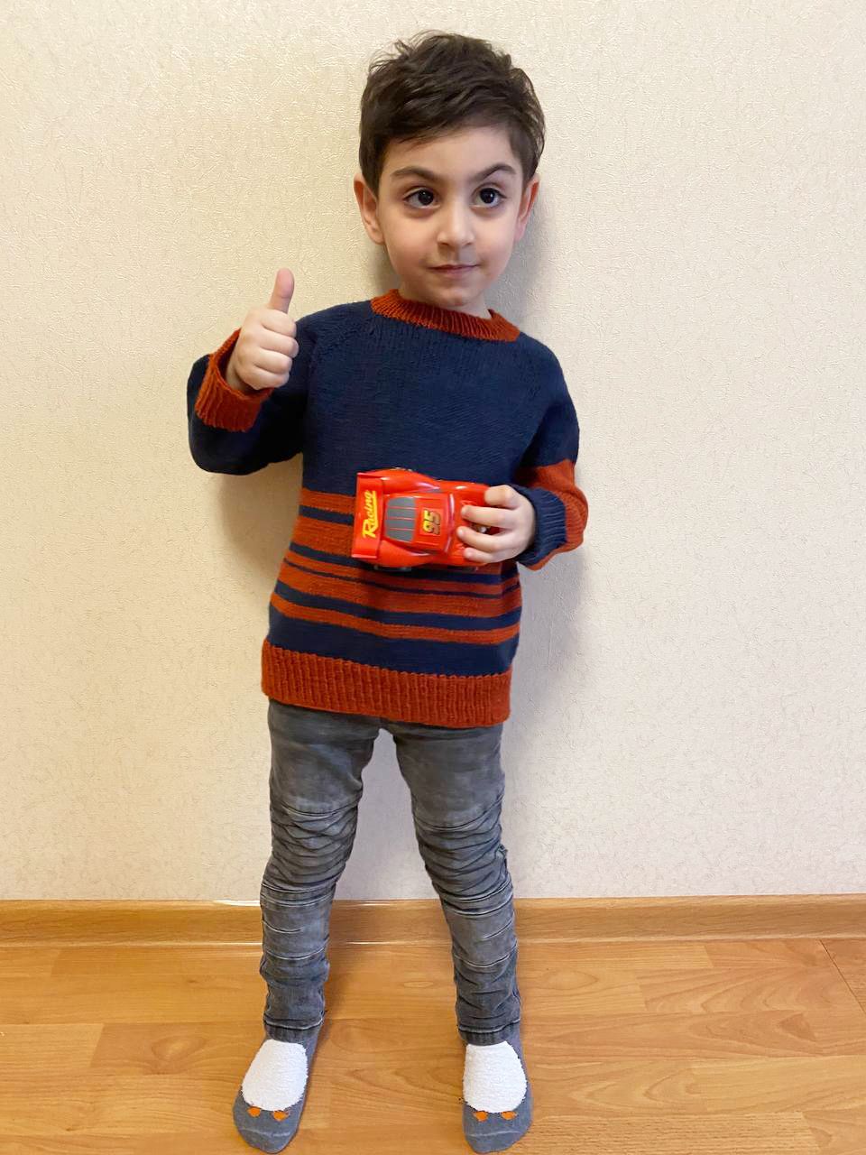 Boy wearing a navy-and-rust striped knitted sweater, front view