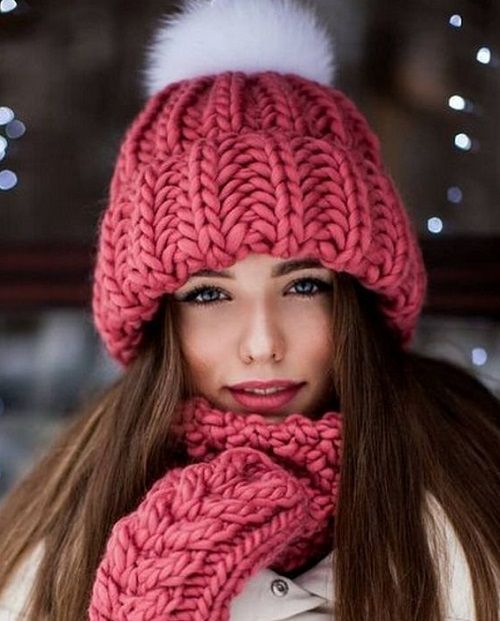 A pink hat with a pompom and a textured pattern