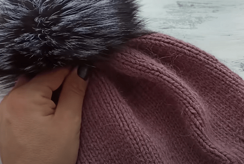A finished fluffy-yarn hat with a fur pompom
