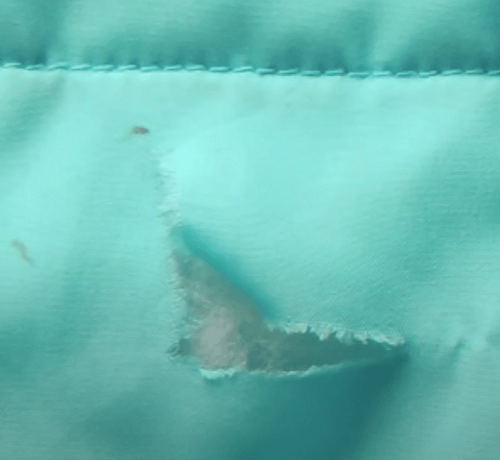 Small tear in raincoat fabric prepared for an adhesive patch