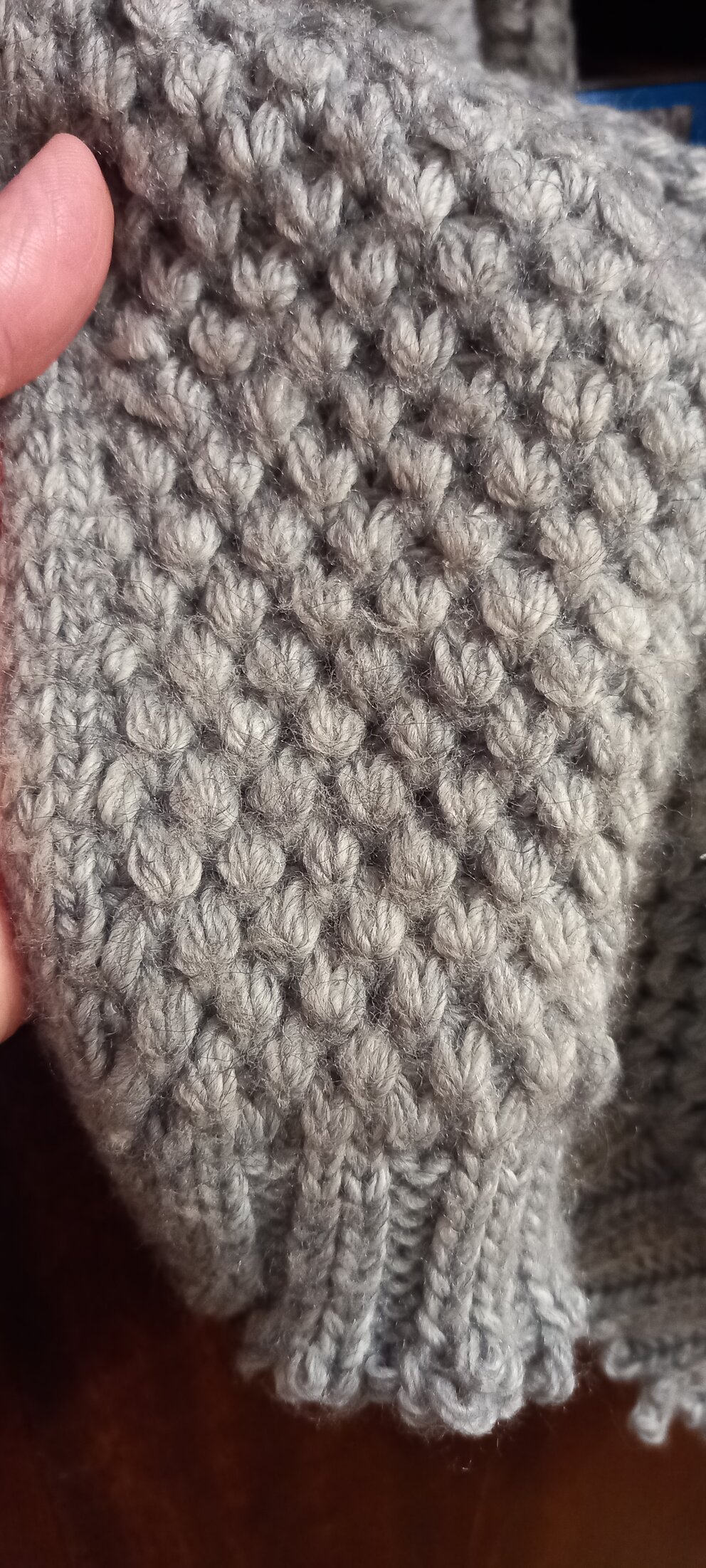 Close-up of a grey knitted pattern with ribbing along the edge