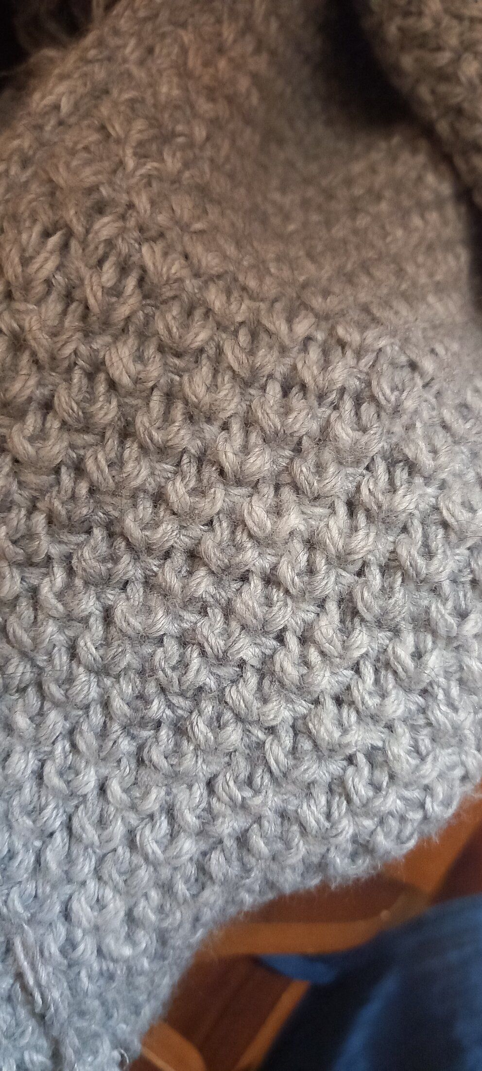 Fragment of a grey scarf or cowl with a dense textured pattern