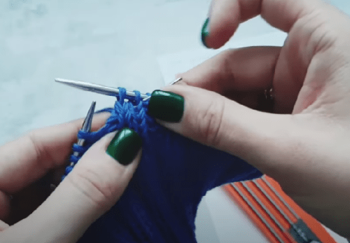 A crown decrease through the back loop on blue fabric