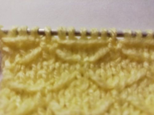 Yellow Butterfly stitch swatch on knitting needles