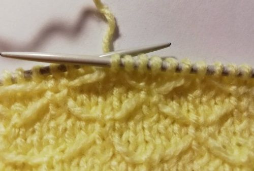 Knitting a stitch in the yellow Butterfly stitch pattern