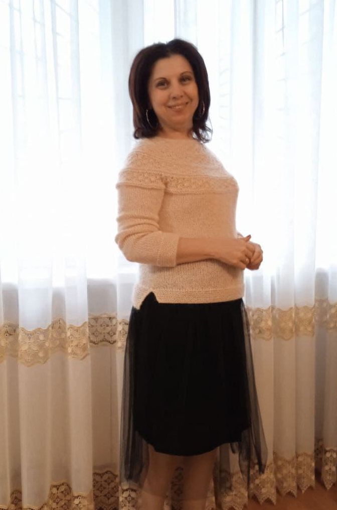 Светлый джемпер с круглой кокеткой на модели у окна