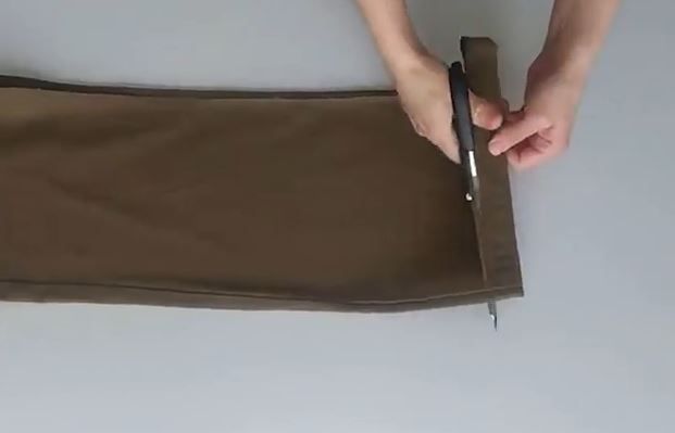 Cutting away the folded lower hem from the trouser leg