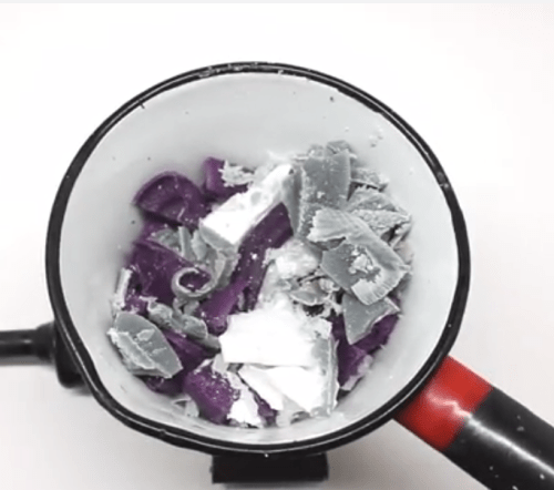 Archival photograph of purple and white wax pieces in an enamel pan set on direct heat