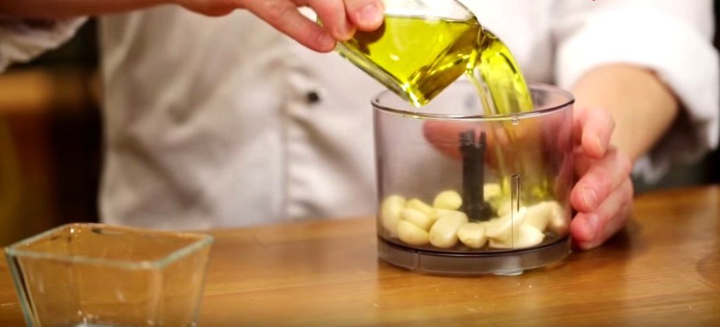Масло наливают к очищенным зубчикам чеснока в чаше кухонного комбайна