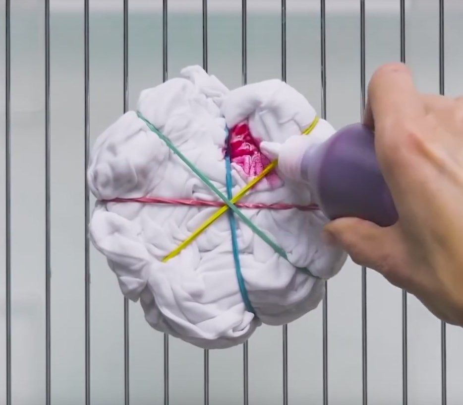 Applying fabric dye to a rubber-banded T-shirt bundle