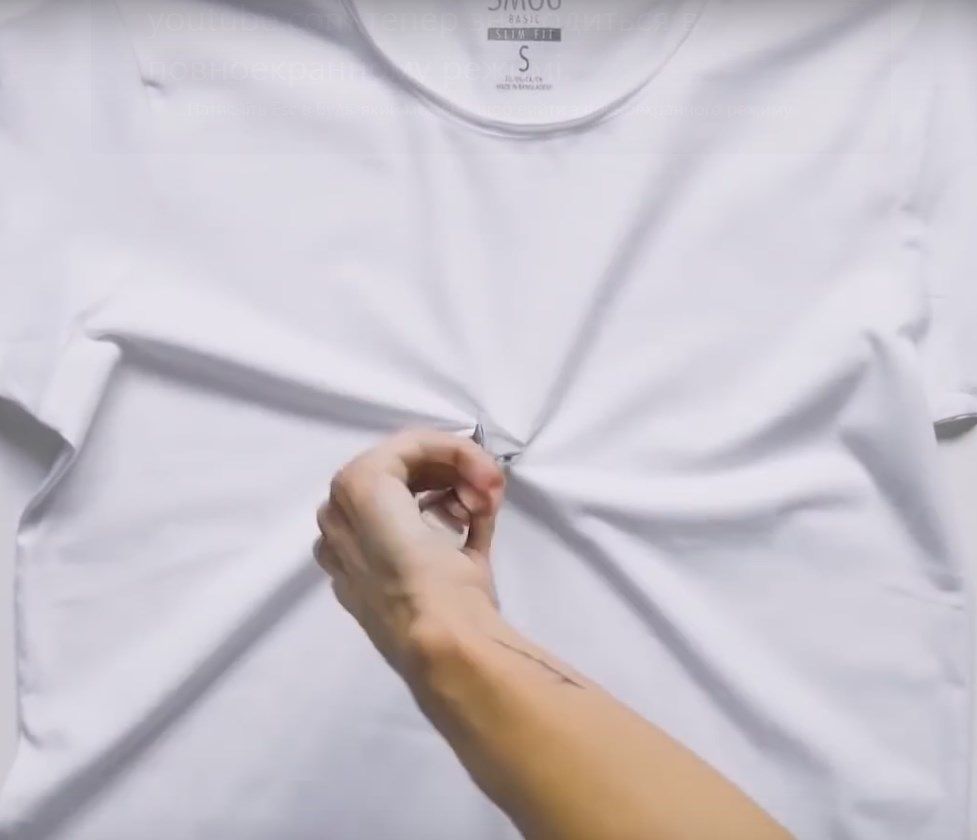Pinching the center of a white T-shirt before twisting