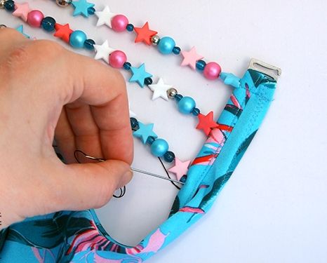 Pinning beaded strands to the edge of the blue swimsuit
