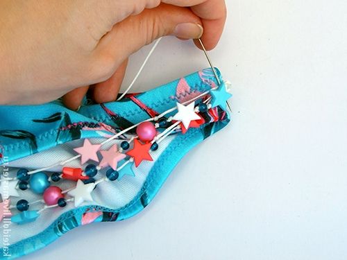 Sewing the bead decoration onto the blue swimsuit