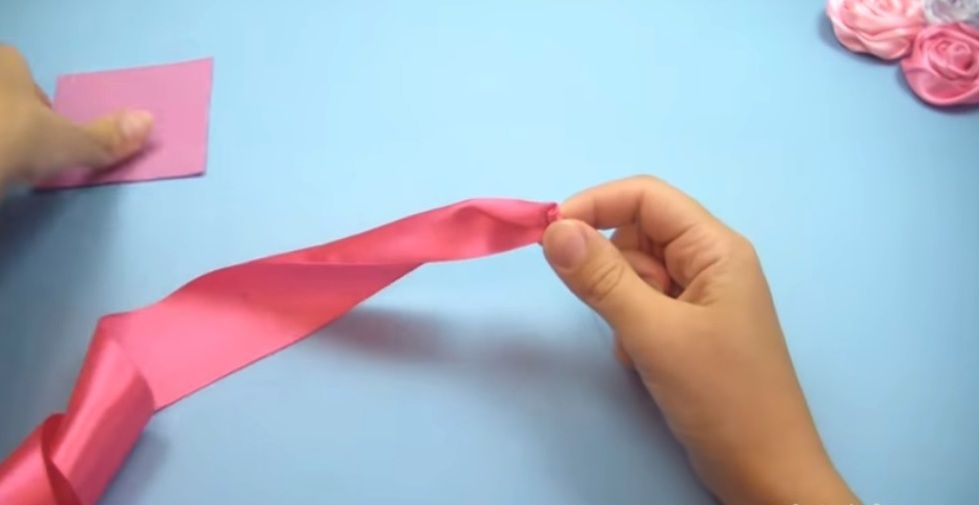 Starting rosebud made of satin ribbon next to a felt base