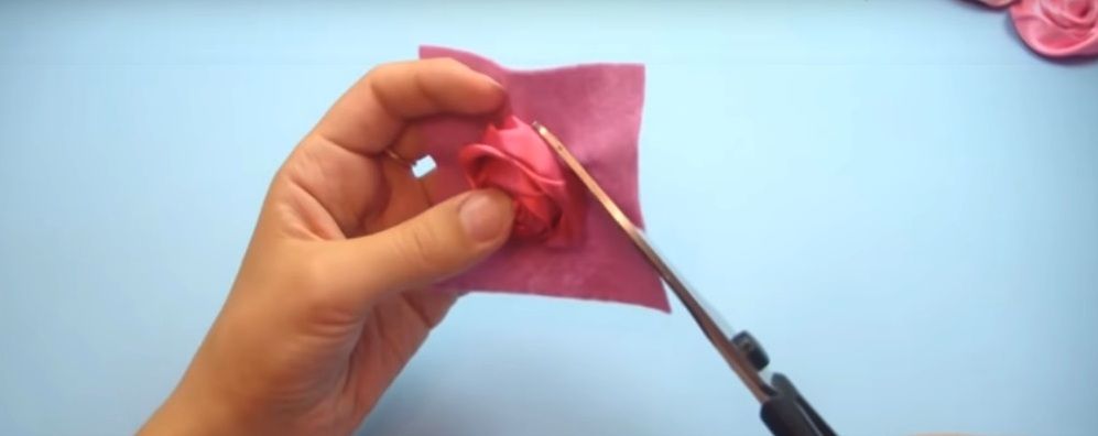 Trimming excess felt under a sew-on satin ribbon rose