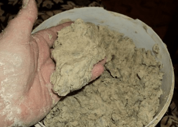 Рука держит комок серой смеси бумаги и шпаклёвки