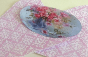 Oval cutout with a floral image on a sheet of ornament paper