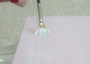 Applying light paint over the box's pink surface