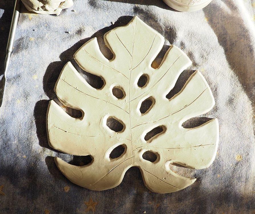 Smoothed clay monstera leaf before shaping in a bowl