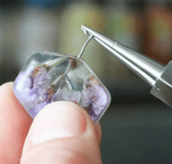Inserting the heated loop into the resin pendant