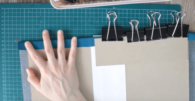 Cardboard parts held under a press while being covered with faux leather
