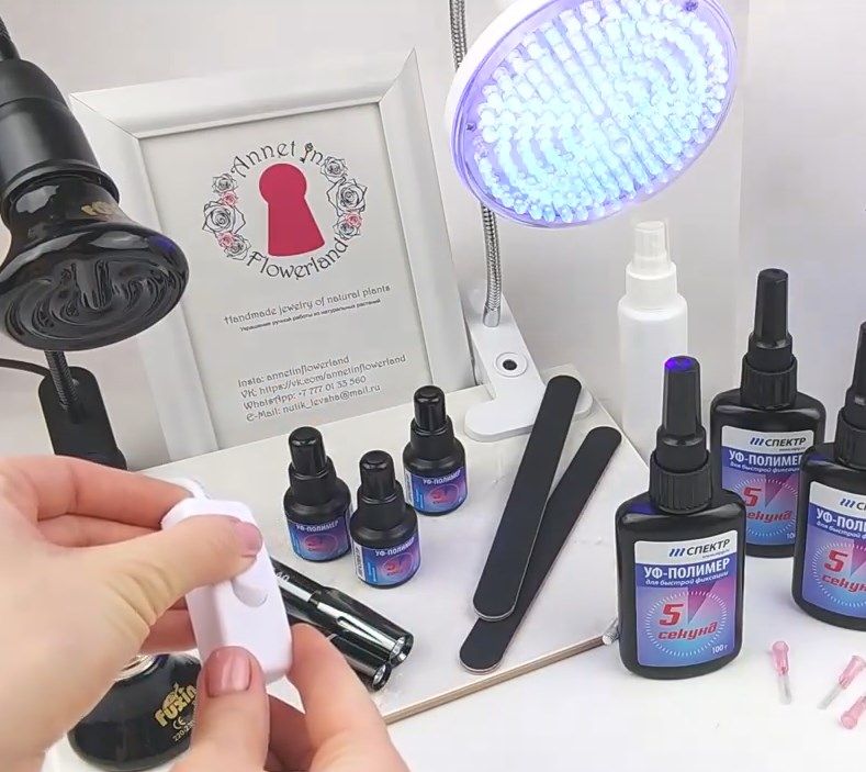 UV-resin work area with resin and pigment bottles, tweezers, files, and two UV lamps