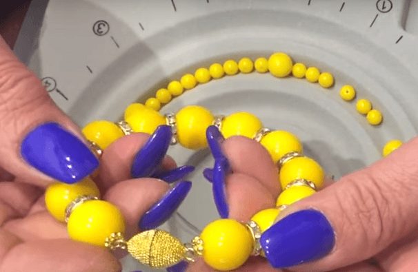 Yellow beads being strung onto wire