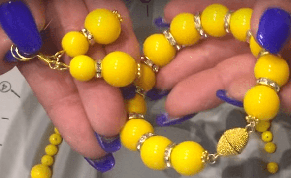 Yellow beaded bracelet with a gold-tone clasp in hands