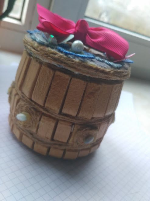 A handmade box made from a tin can and clothespins