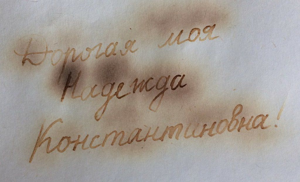 Коричневая надпись, проявившаяся от нагрева на белой бумаге в архивной демонстрации невидимых чернил
