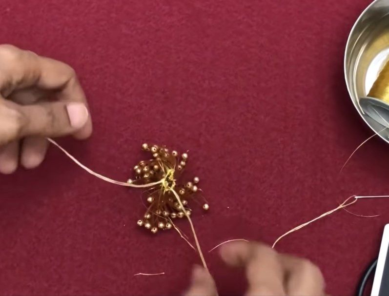 Cinching a bundle of threads around a pin to form the base of the tassel