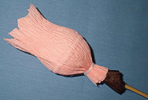 Candy on a skewer wrapped in pink crepe paper in the shape of a bud