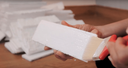 Applying glue to the back of a Styrofoam brick