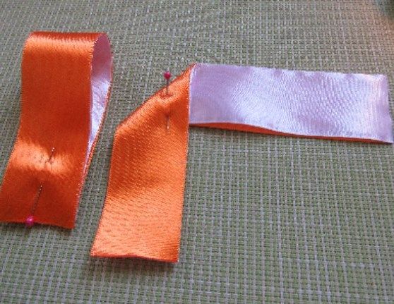 Two-tone ribbon folded into an angle and secured with a pin