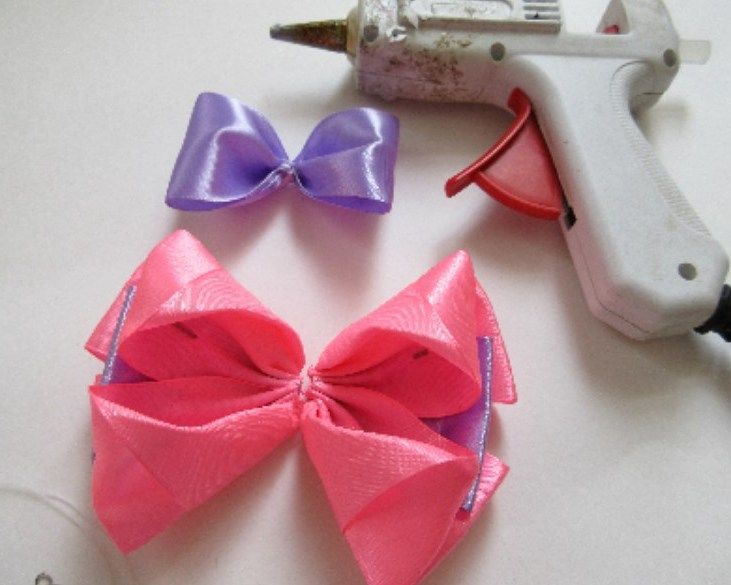 Lilac bow and pink bow pieces beside a glue gun