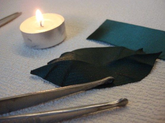 Заготовка зеленого листочка з атласної стрічки біля свічки