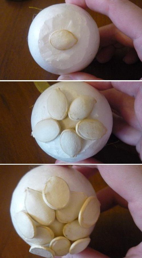 Pumpkin seeds being glued step-by-step to a foam ball