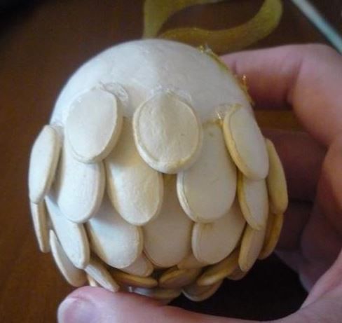 Ball partially covered with pumpkin seeds