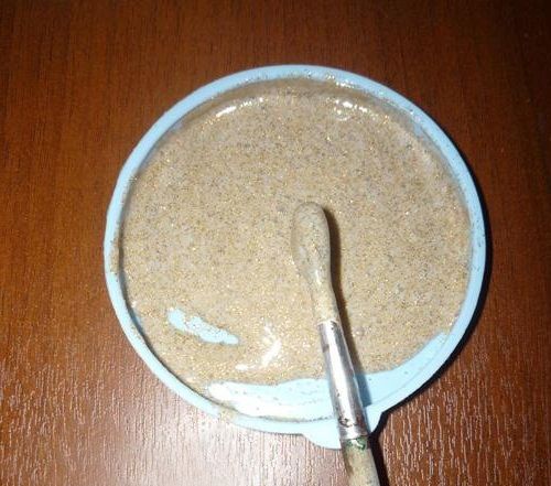 Paintbrush in a bowl with a mixture of glue and gold glitter