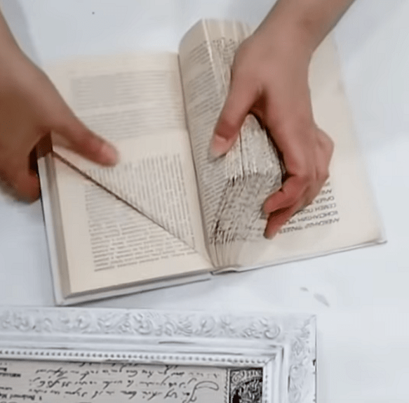Folding the bottom corner of a book page into a triangle