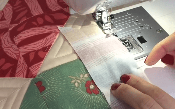 Stitching the binding to the corner of a patchwork project on a sewing machine