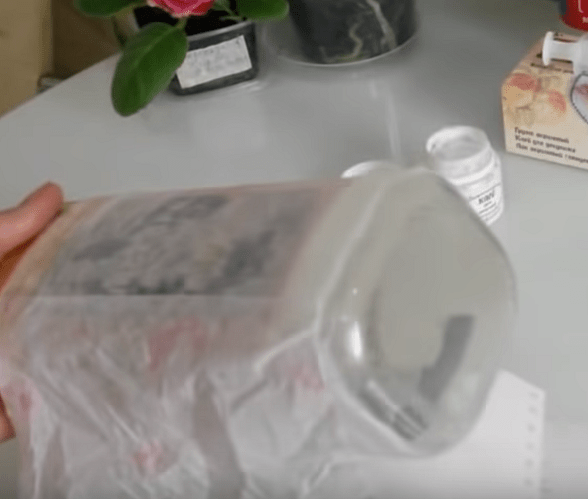 Paper napkin being glued onto a jar before decoupage