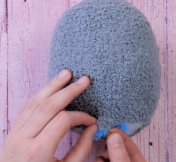 Shaping the body of the penguin toy from a gray sock
