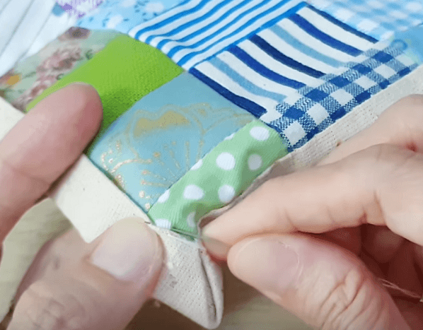 Hand-hemming the folded corner of the napkin with an invisible stitch