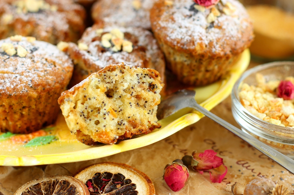 Cut apple and poppy-seed muffin on a yellow plate with more muffins behind it